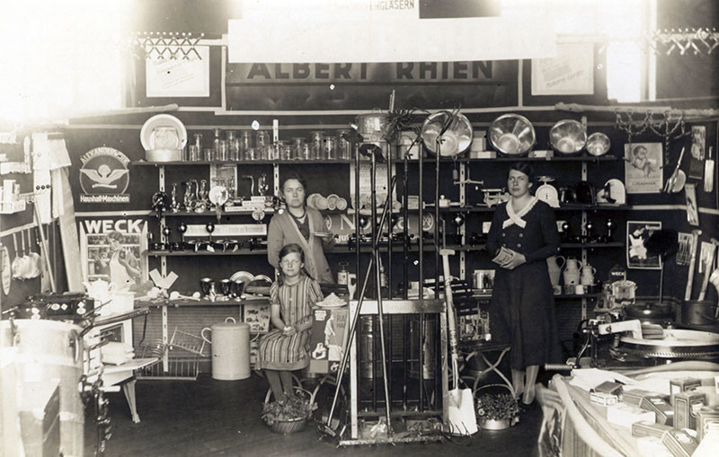 Stand der Firma Rhien in der Turnhalle, Postkarte 1933 (Bernd Voigtländer) Unter den Ausstellern befand sich die Eisenwarenhandlung von Albert Rhien. Links im Bild Martha Rhien mit ihrer Tochter Elfriede.