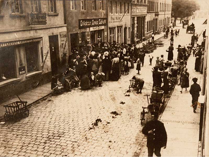 Schlangestehen im Kohlrübenwinter 1917. Vor dem Delikatessen-Geschäft Heinrich Messlin in der Langen Straße 9 stehen Frauen in der Hoffnung, dass sie für ihre Lebensmittelkarten auch die entsprechende Ware kaufen können.